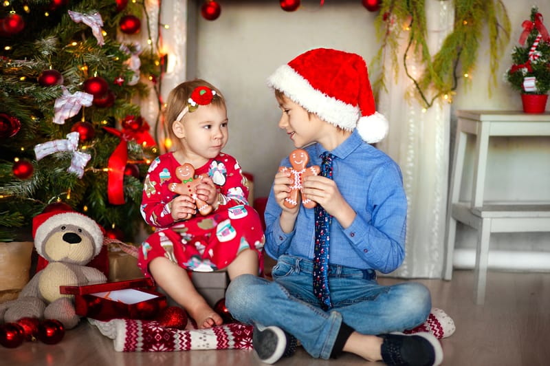 children eating christmas cookie by a tree