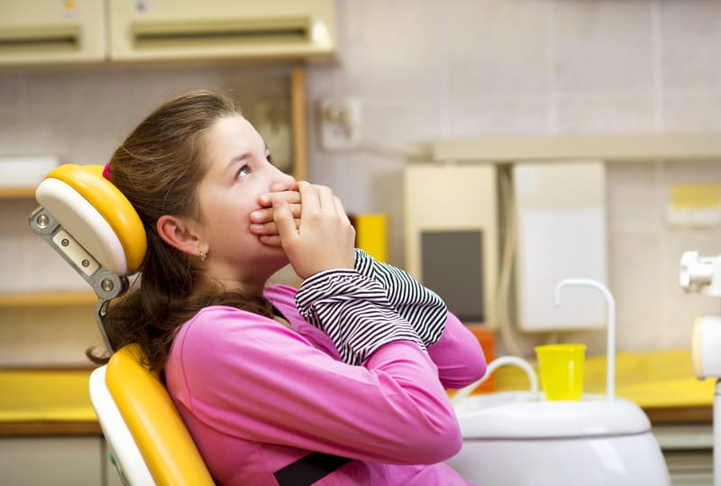 patient holding mouth in dental chair