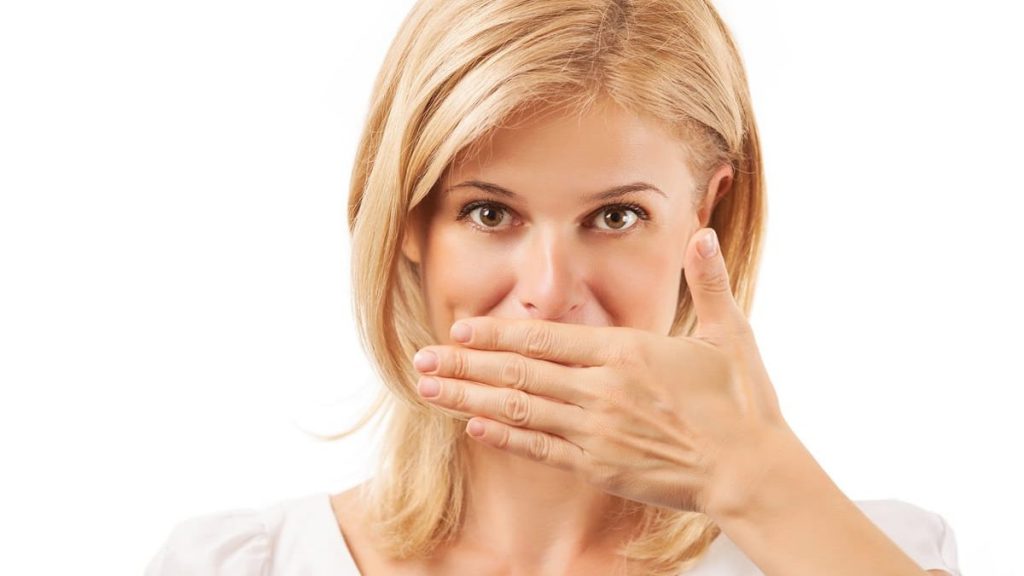 woman covering her mouth from missing tooth