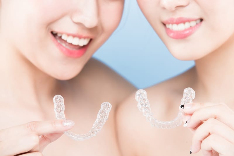 women holding invisaligners