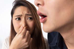 woman with bad breath and her friend holding her nose