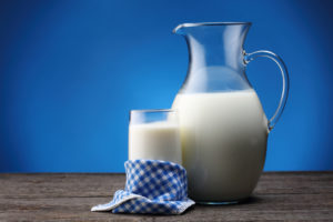 Jar and glass with some milk on blue background